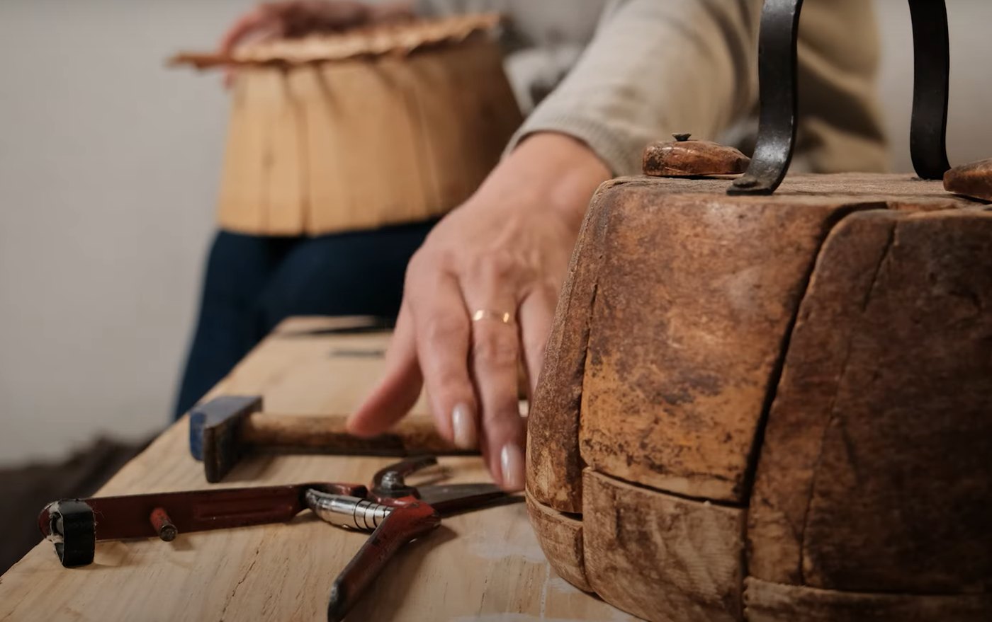Tijeras, martillo y molde de madera para hacer una cesta de mimbre