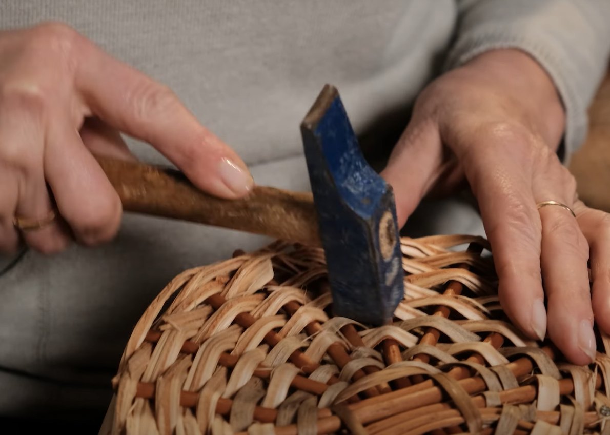 Fondo de mimbre sujeto al molde con martillo y clavos