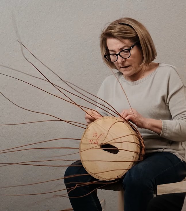 Mercedes trenzando una cesta de mimbre en el taller de Cestería Aparici