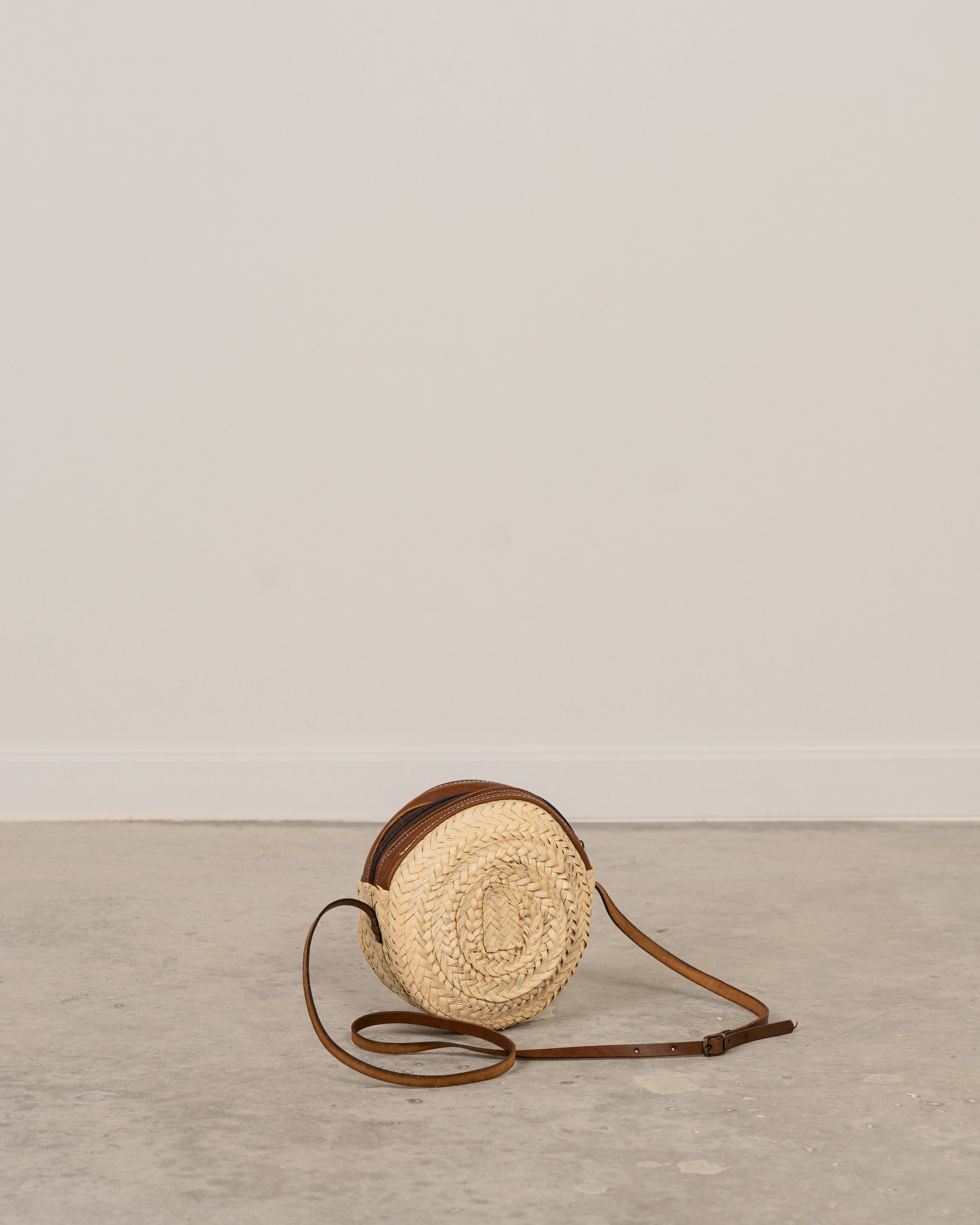 Bolso redondo de palma con asa de cuero
